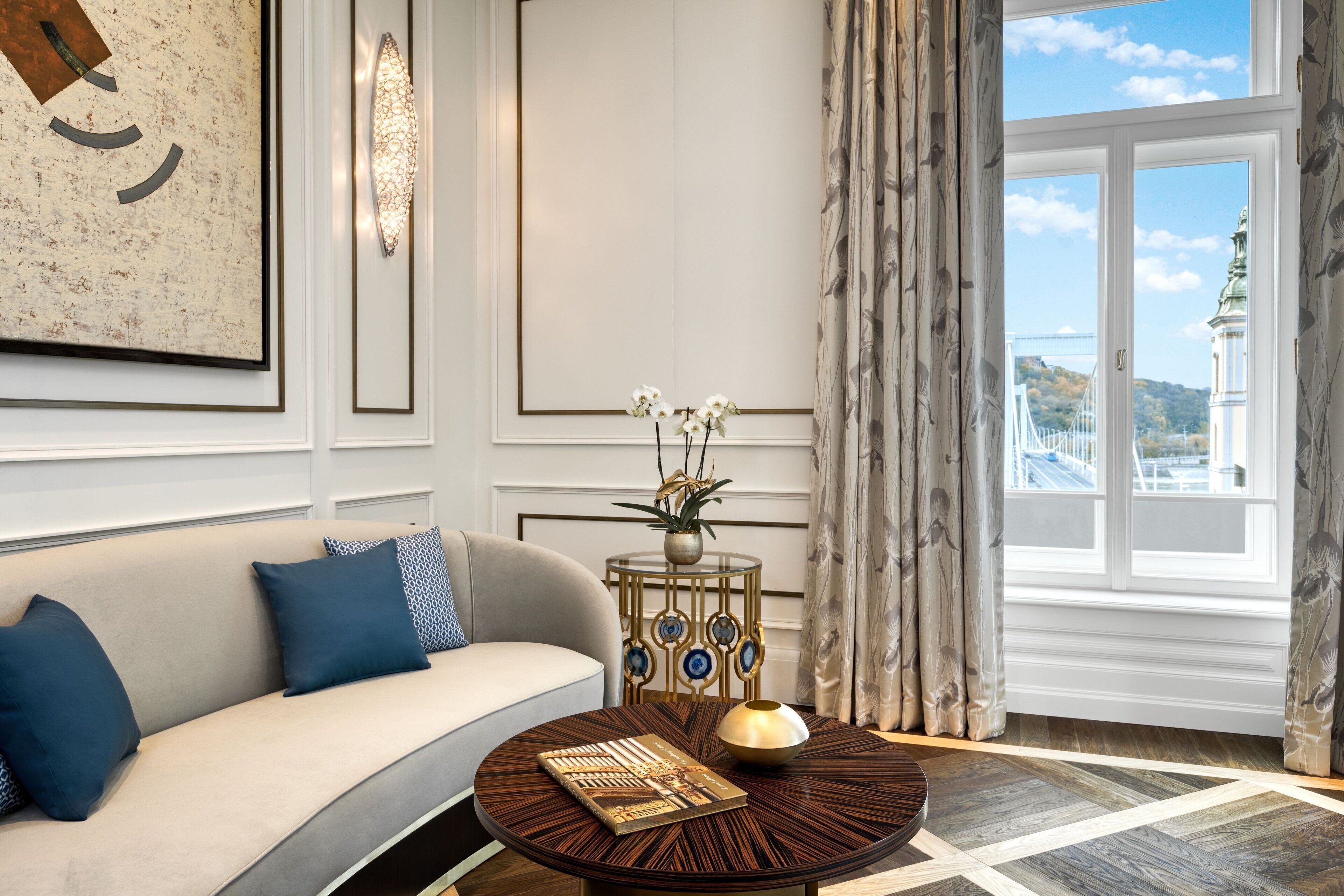 Un salon moderne avec un canapé, une table basse ronde et une petite table d’appoint décorative sur laquelle est posé un vase de fleurs.