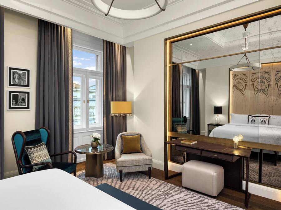Habitación de hotel con cama, escritorio, silla, una mesa redonda y un espejo grande.