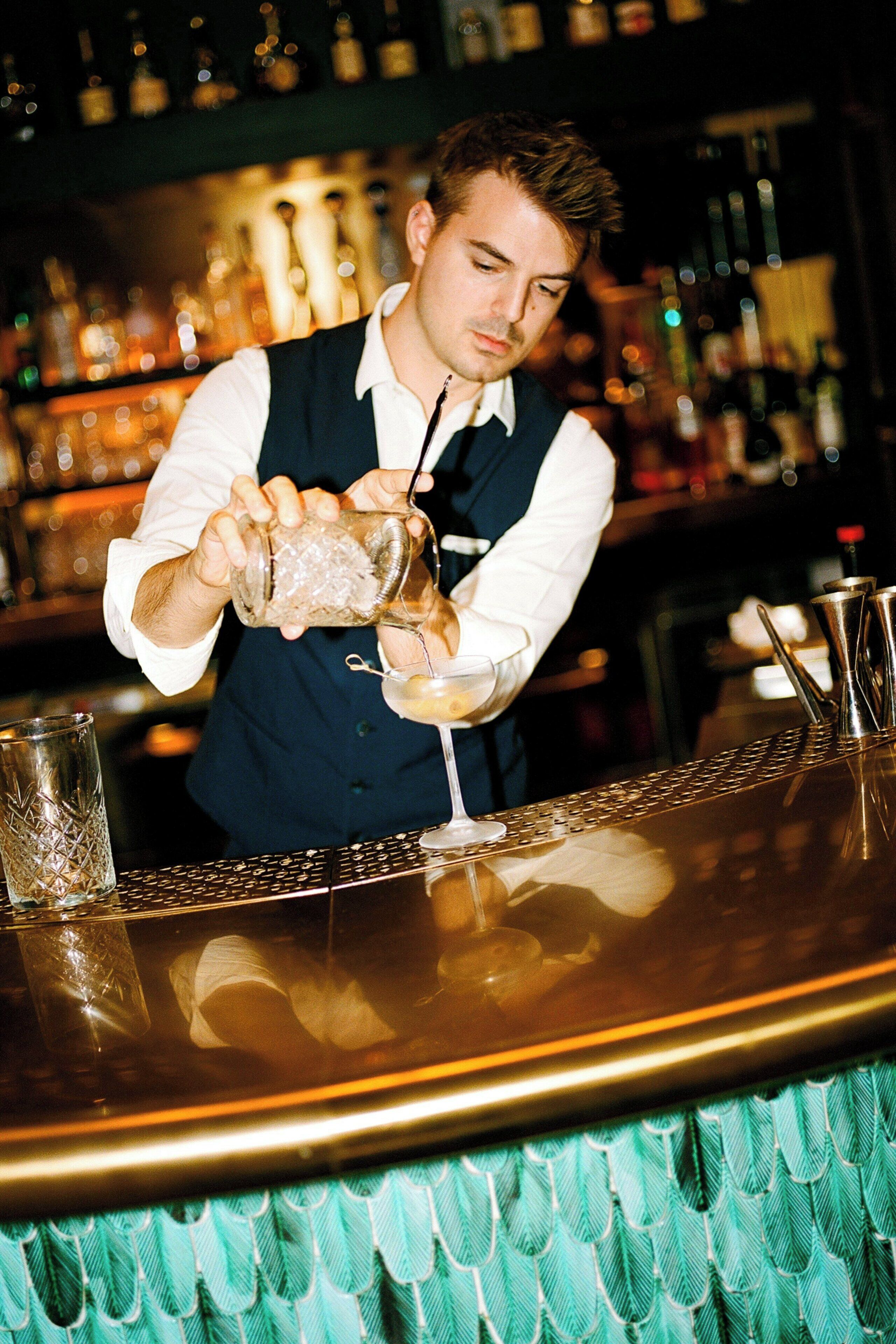 Een bartender schenkt een drankje in een glas.