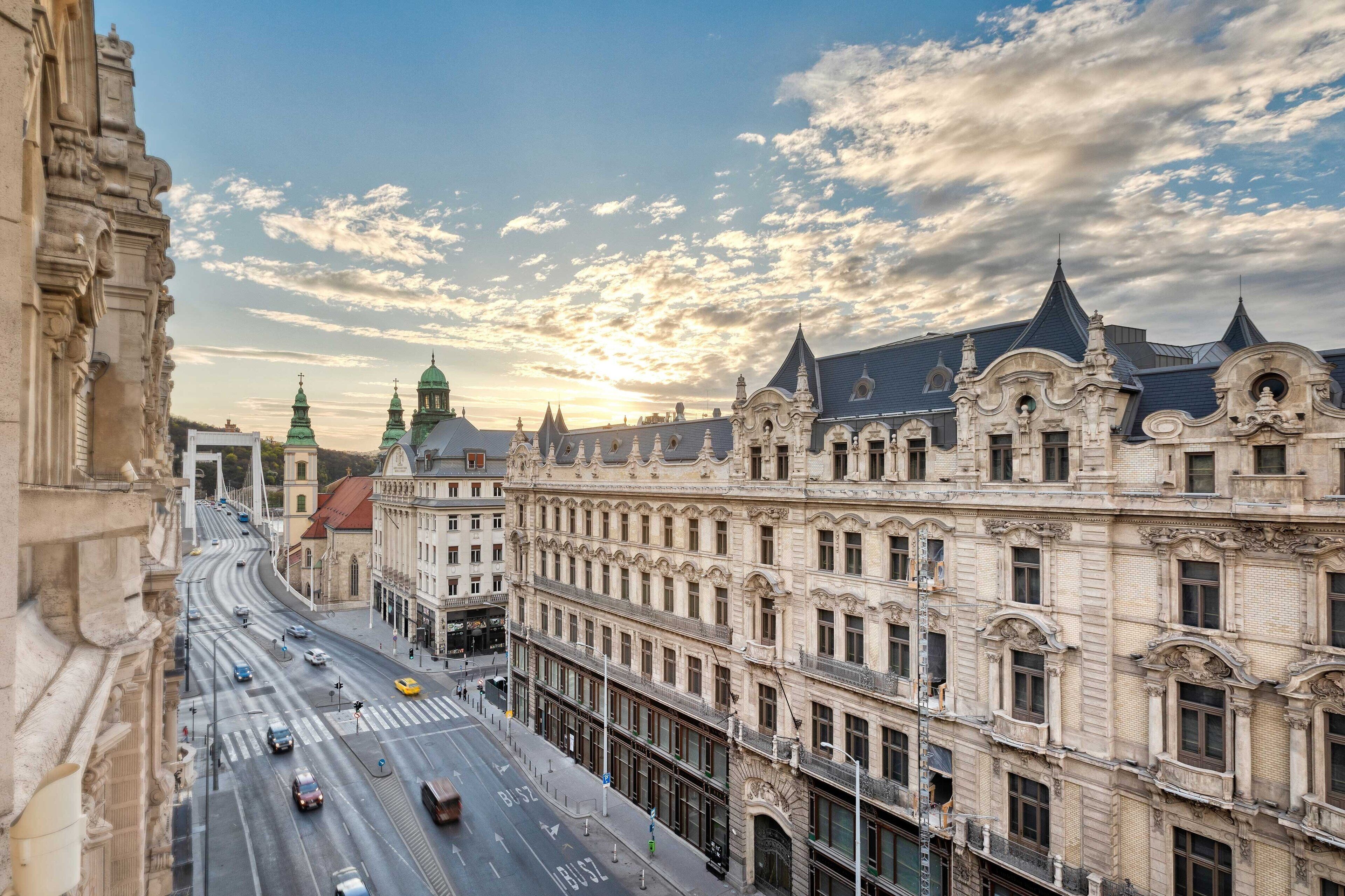 A historic building with classical architecture, a wide street, and a clear sky.