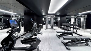 A modern gym with cardio equipment, weight benches, and dumbbells.