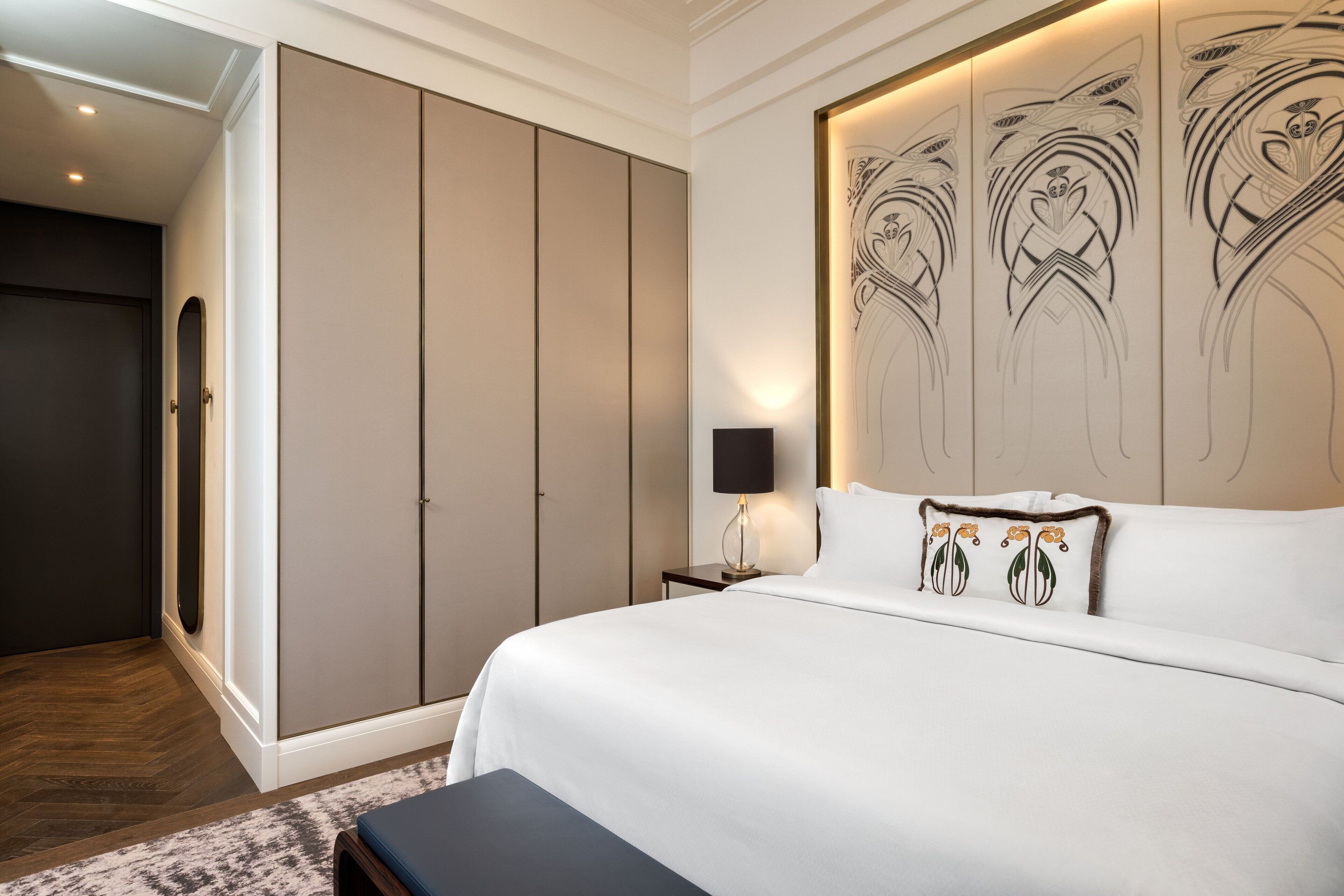 Une chambre à coucher avec un grand lit, une armoire et une table de chevet avec une lampe.