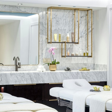 A modern bathroom with a marble countertop, a large mirror, and a spa bed.