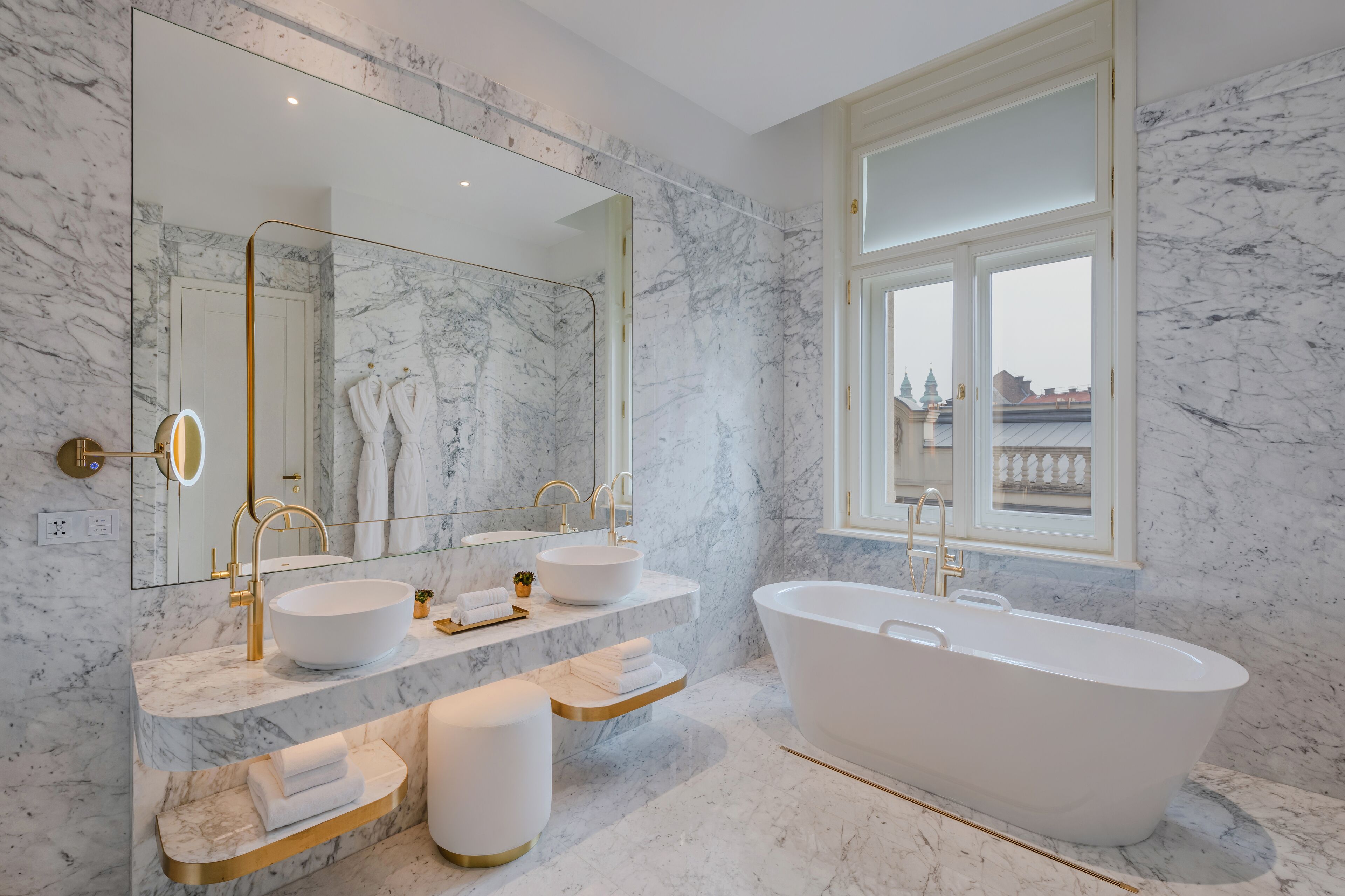 A modern bathroom with a freestanding bathtub, two sinks, and a large mirror.