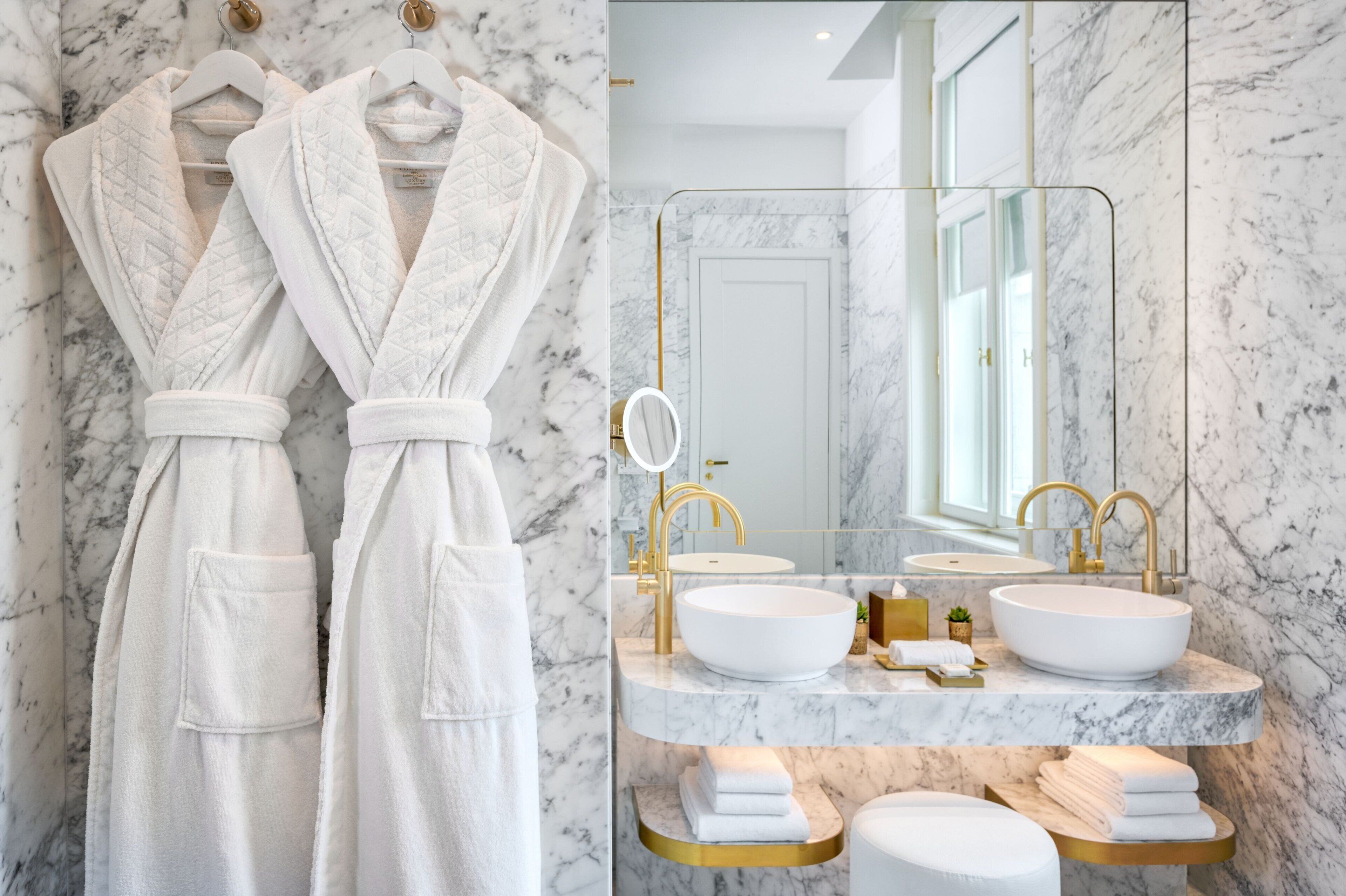 Une salle de bain avec deux vasques en marbre blanc, des robinets dorés et un grand miroir.