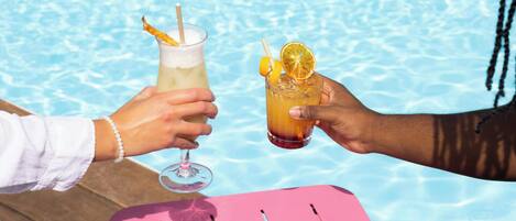 Dos personas brindando con bebidas junto a una piscina.