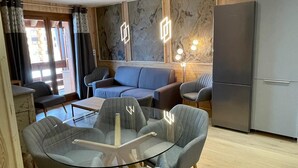 Ein modernes Wohnzimmer mit einem Glastisch, grauen Sofas und einem grauen Kühlschrank.