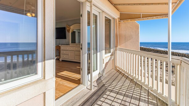 Een balkon met uitzicht op de oceaan, een houten vloer en een witte balustrade.