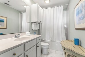 Ein Badezimmer mit Waschbecken, Spiegel, Toilette und Duschvorhang.