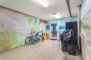Un couloir orné d’une fresque murale, avec des vélos, une porte et un objet recouvert d’un tissu.