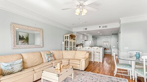 Een woonkamer met een beige hoekbank, een salontafel en een kamerkleed met patroon.