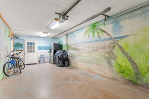 Ein Zimmer mit Wandgemälde einer Strandansicht, einem Fahrrad und einem bedeckten Gegenstand.