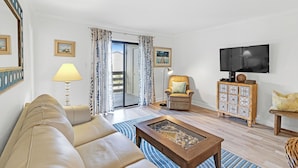 Een woonkamer met een bank, salontafel, televisie, stoel en kast.