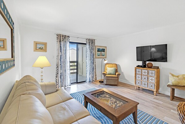 A living room with a sofa, a coffee table, a TV, a chair, and a cabinet.