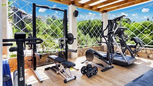 An outdoor gym with exercise equipment, including a bench, dumbbells, and a weight machine. - Sorrento Dream Villa (Sorrento)