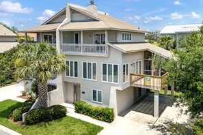 A multi-story residential building with a balcony, a covered entryway, and a well-maintained lawn. - Tybee Townhome: Ocean Views & Private Path to the Beach (Tybee Island)
