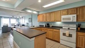 A modern kitchen with wooden cabinets, a central island, a microwave, and a stove. - South Beach Escape | Ocean Views + Walkable Fun (Tybee Island)