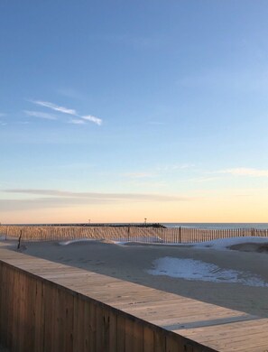 Une promenade en bois longeant une plage, sous un ciel dégagé.