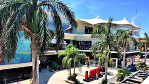 A multi-level shopping mall with palm trees, a large 'LOVE' sign, and a glass building with a sign that reads 'Coca-Cola'. - Hotel Mariachi by Kavia 5th Av (Playa del Carmen)