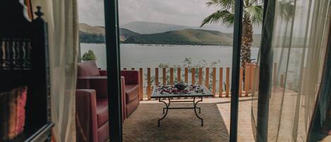 A room with a view of a lake and mountains through a glass door.