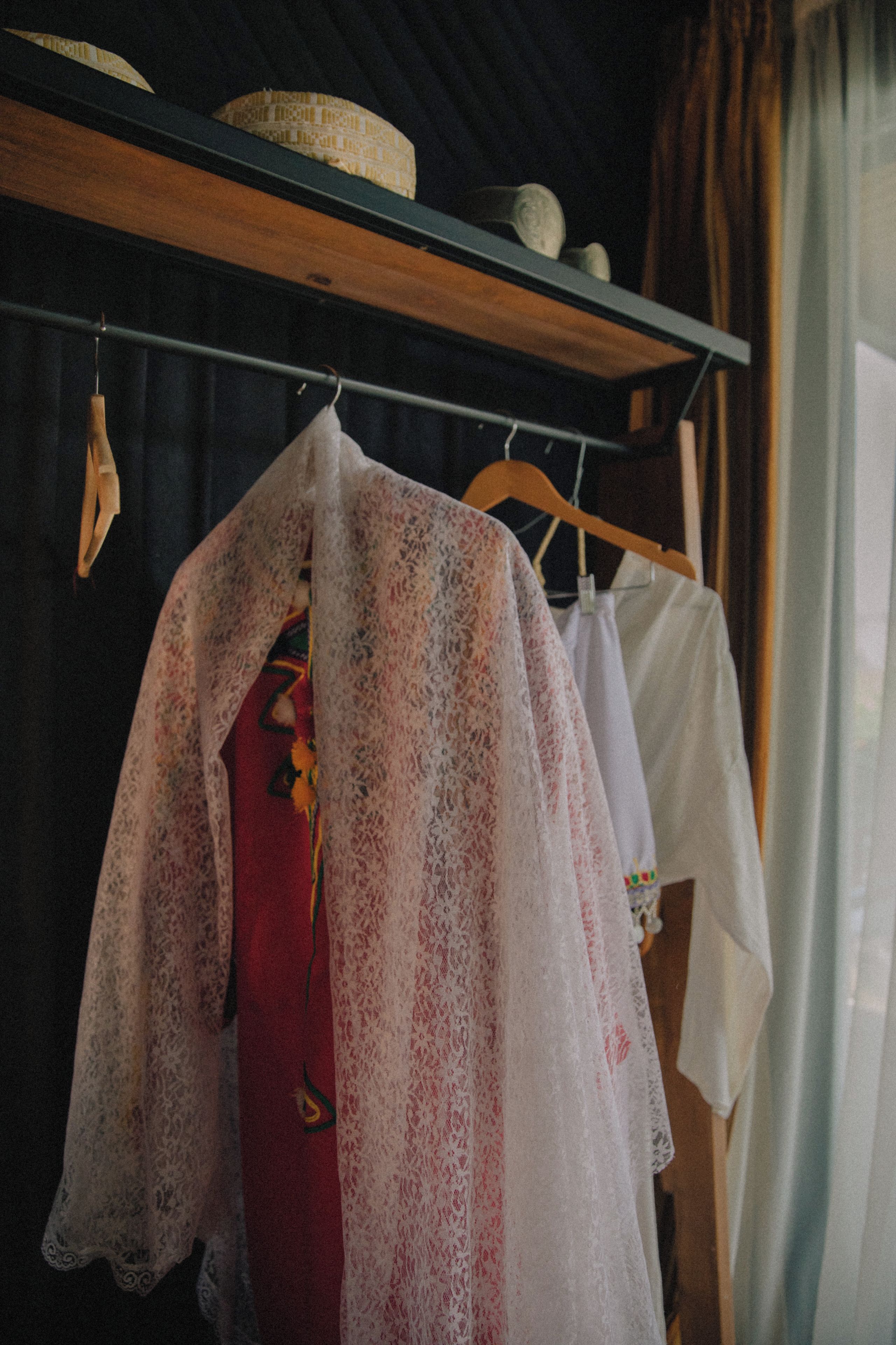 Un appendiabiti con diversi capi di abbigliamento, tra cui un vestito rosso e camicie bianche.