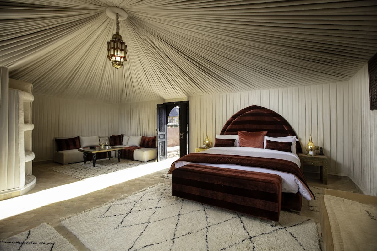 Um quarto com uma cama grande, um sofá, uma mesa e um candelabro.