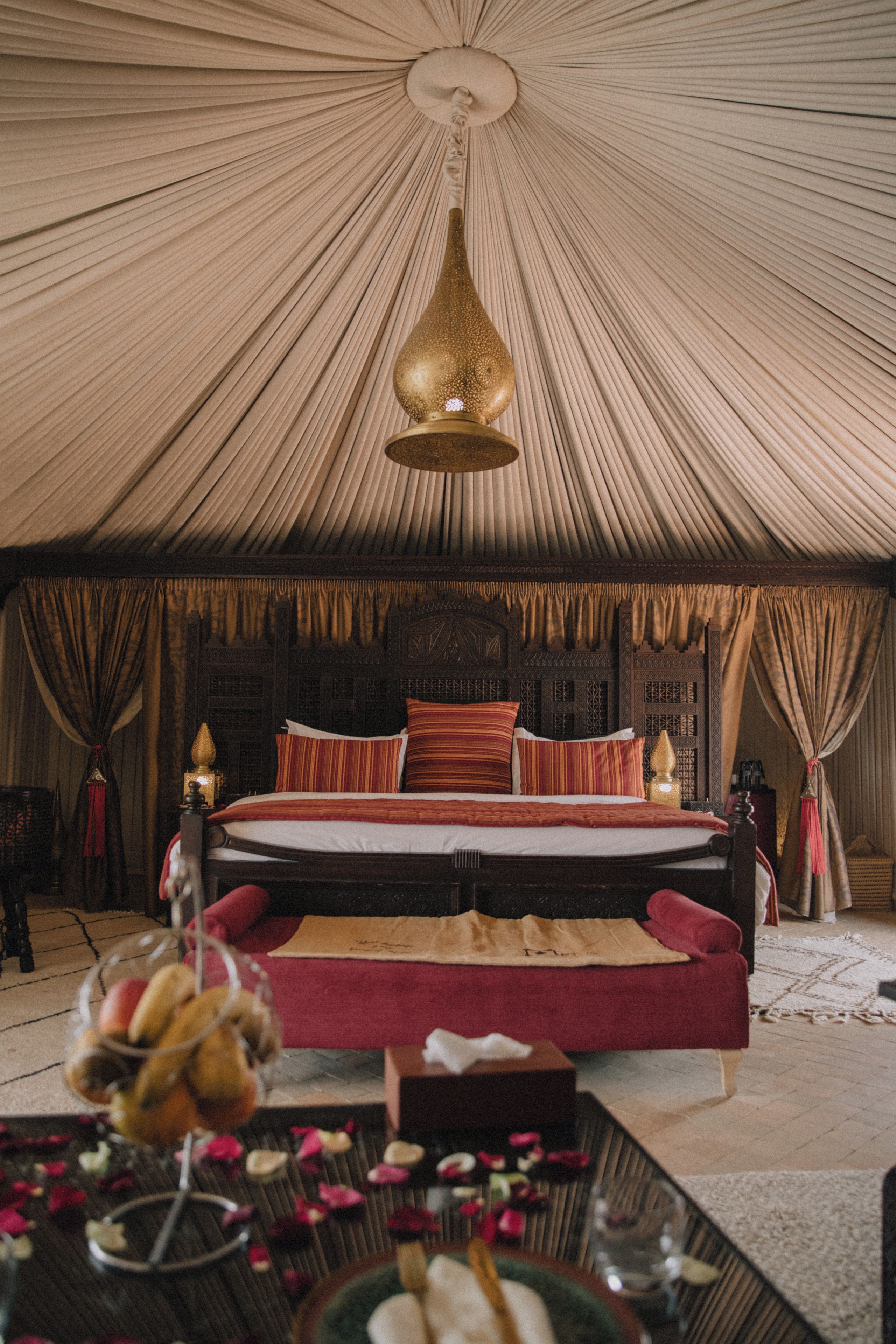 A tented room with a bed, pillows, and a hanging light fixture.