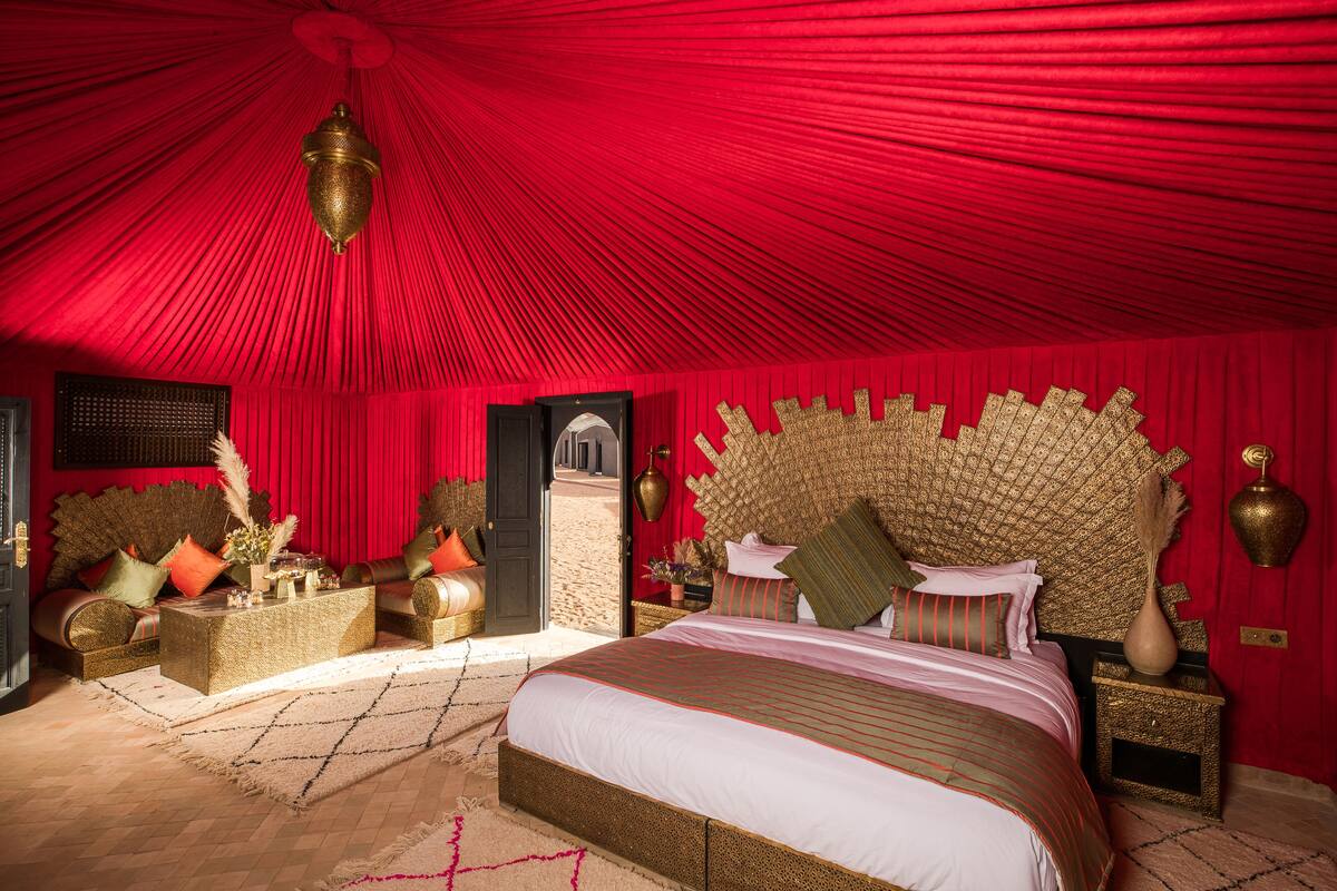Um quarto luxuoso com uma cama grande, um dossel vermelho e decoração requintada.