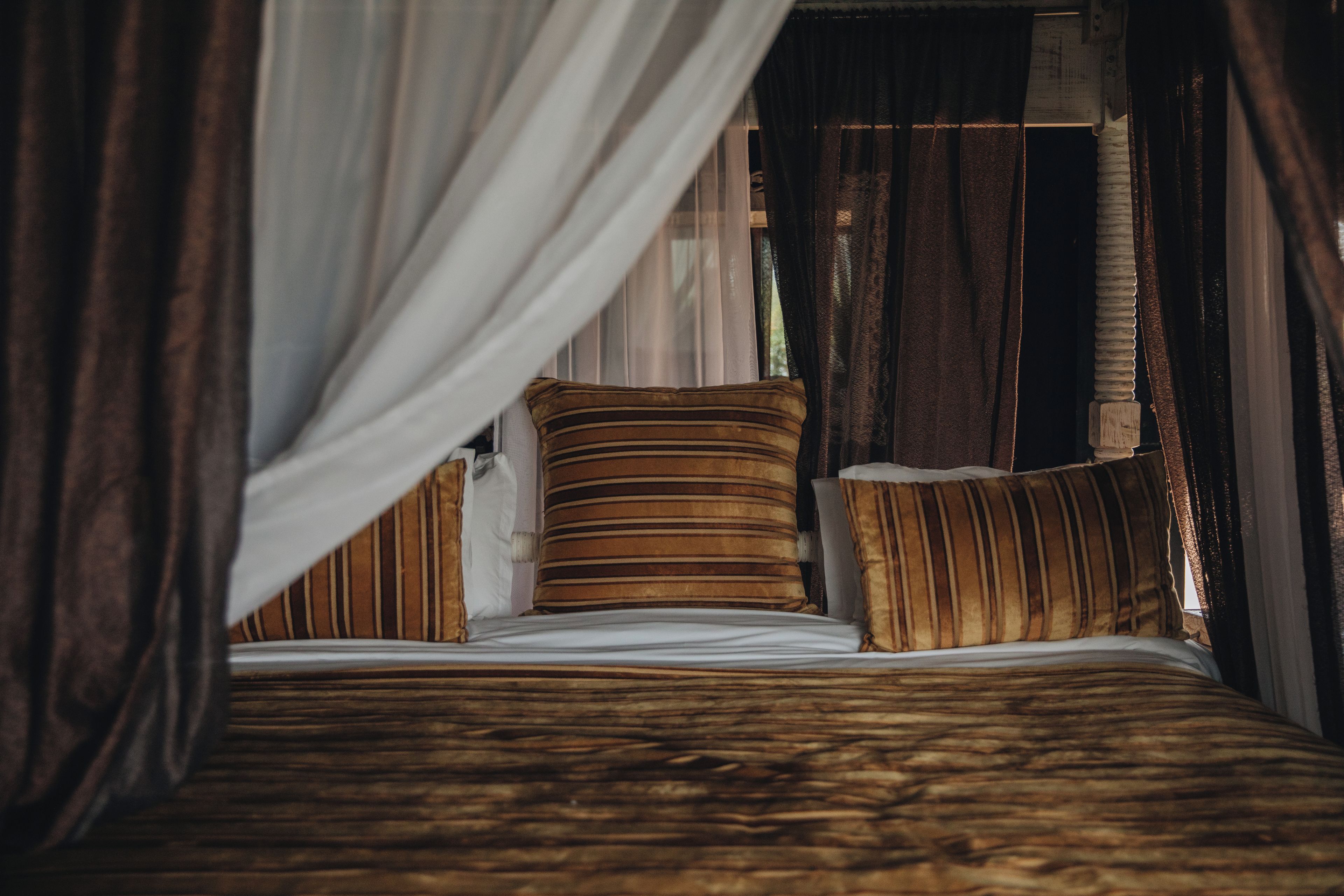 Een bed met gestreepte lakens, een kussen en een hemelbed.