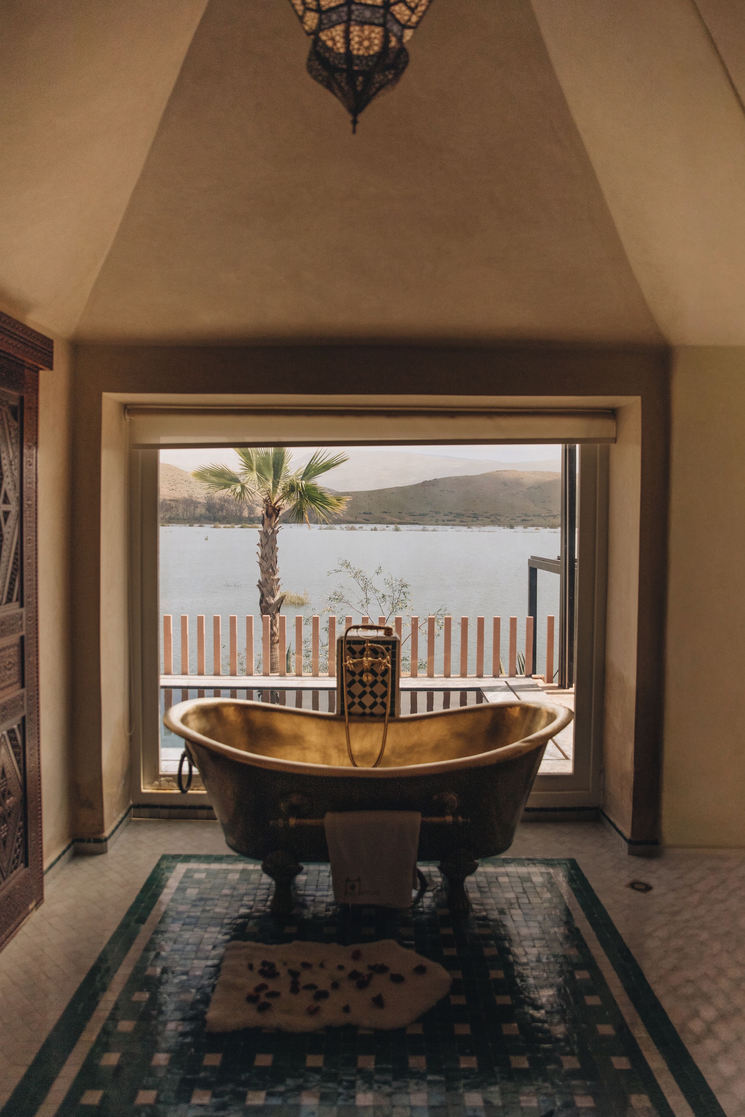 Una bañera en una habitación con vistas a un lago y montañas.