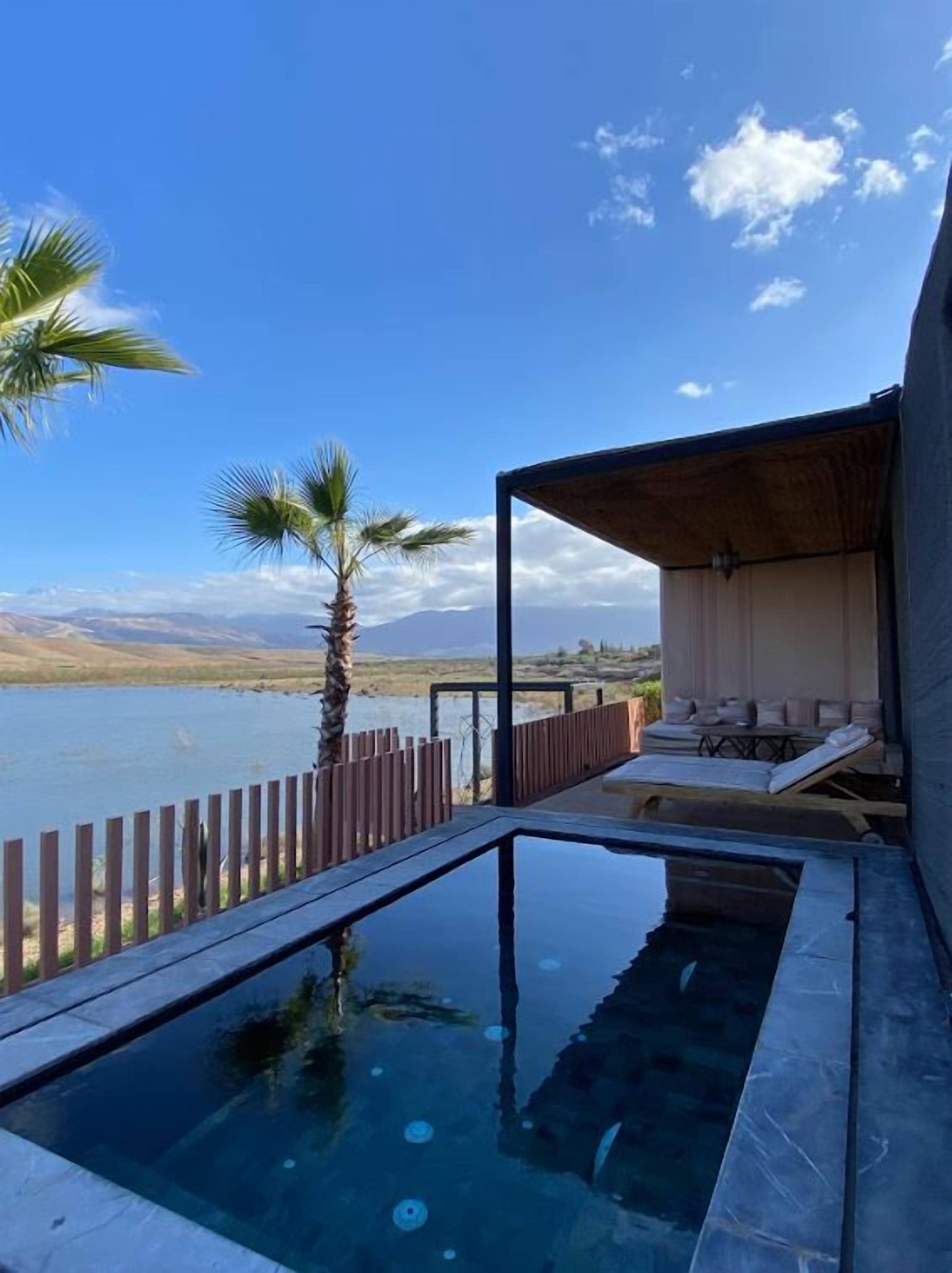 A pool with a wooden deck, lounge chairs, and a view of the landscape.