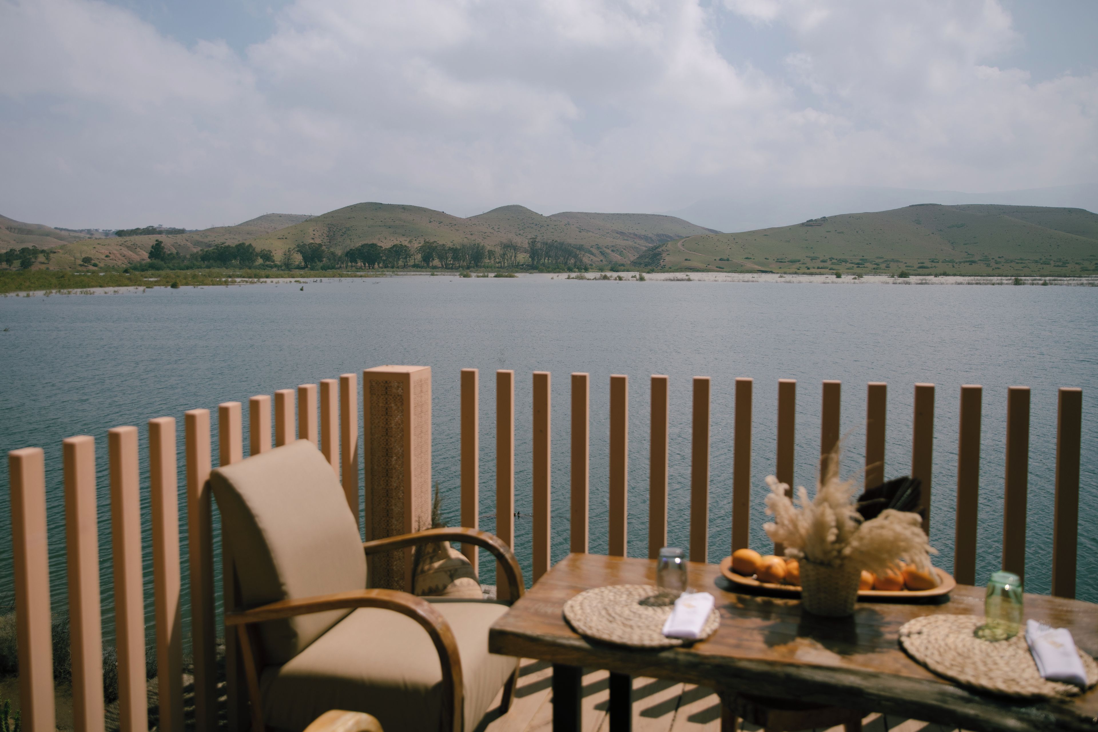 A dining table with a view of a lake and hills in the background.
