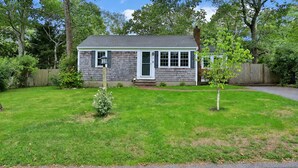 A single-story house with a front yard, a small tree, and a wooden fence. - Dennis Beach House - Walk to Beach - Pet Friendly (Dennis)