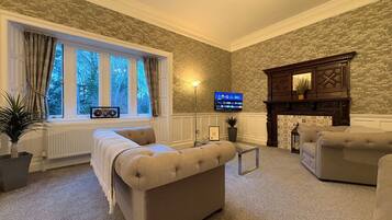 A cozy living room with a fireplace, comfortable seating, a television, and a view of the outdoors.