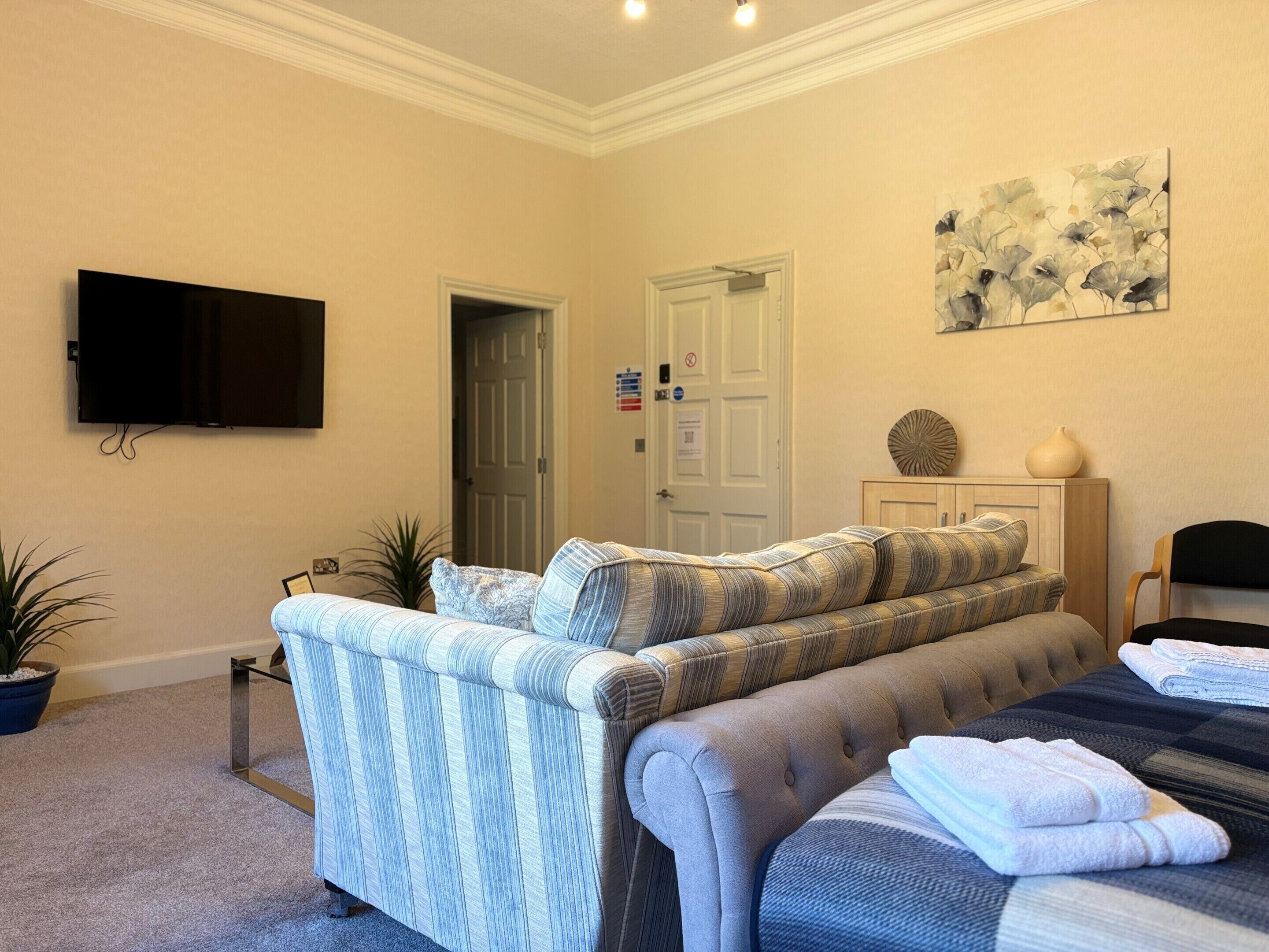 Ein Schlafzimmer mit einem Bett, einem Fernseher, einer Tür und einem an der Wand befestigten Kunstwerk.