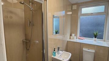 A bathroom with a glass-enclosed shower, a sink, a toilet, and a window with a view of the outside.