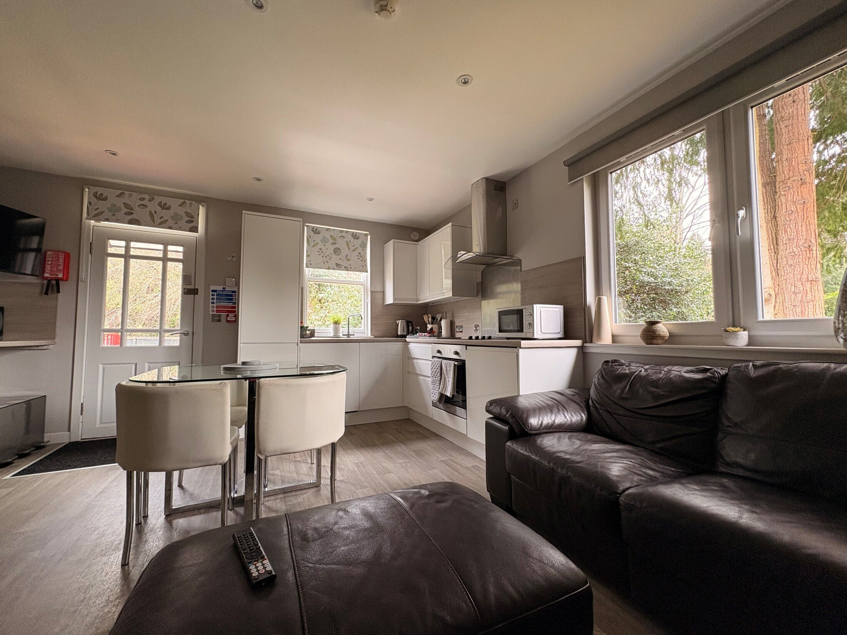 A modern kitchen with white cabinets, a microwave, and a dining area with a glass table and chairs.