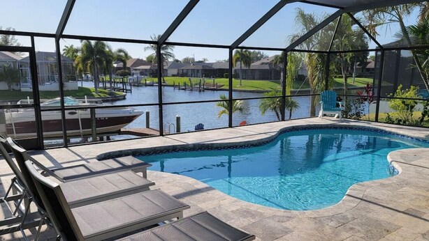 A swimming pool with a view of a marina and palm trees.
