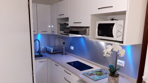Una cocina moderna con armarios blancos, un microondas, un tostador y un lavabo.