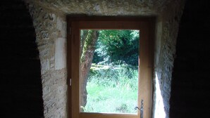 Un vano de entrada en piedra que conduce a una puerta de madera con un ventanal.