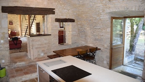 Un interior rústico de piedra con una mesa de comedor de madera, una estufa empotrada y vistas al exterior.