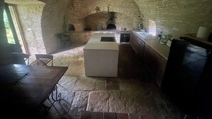 Cocina con paredes de piedra, una isla central, horno empotrado y un fregadero.