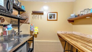 Une cuisine de taille réduite, dotée d’un évier, d’appareils électroménagers en acier inoxydable et d’une table en bois.