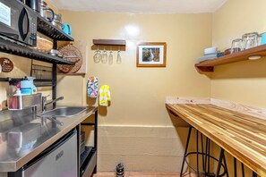 A compact kitchen with a sink, stainless steel appliances, and a wooden table. - Enchanted Waterfall Sanctuary (Mill Valley)