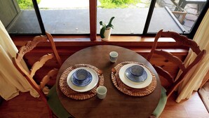 Une table ronde en bois, avec deux assiettes, deux tasses et une petite plante en pot.