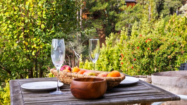 Une table en bois avec un panier de fruits, un verre à vin et un bol.
