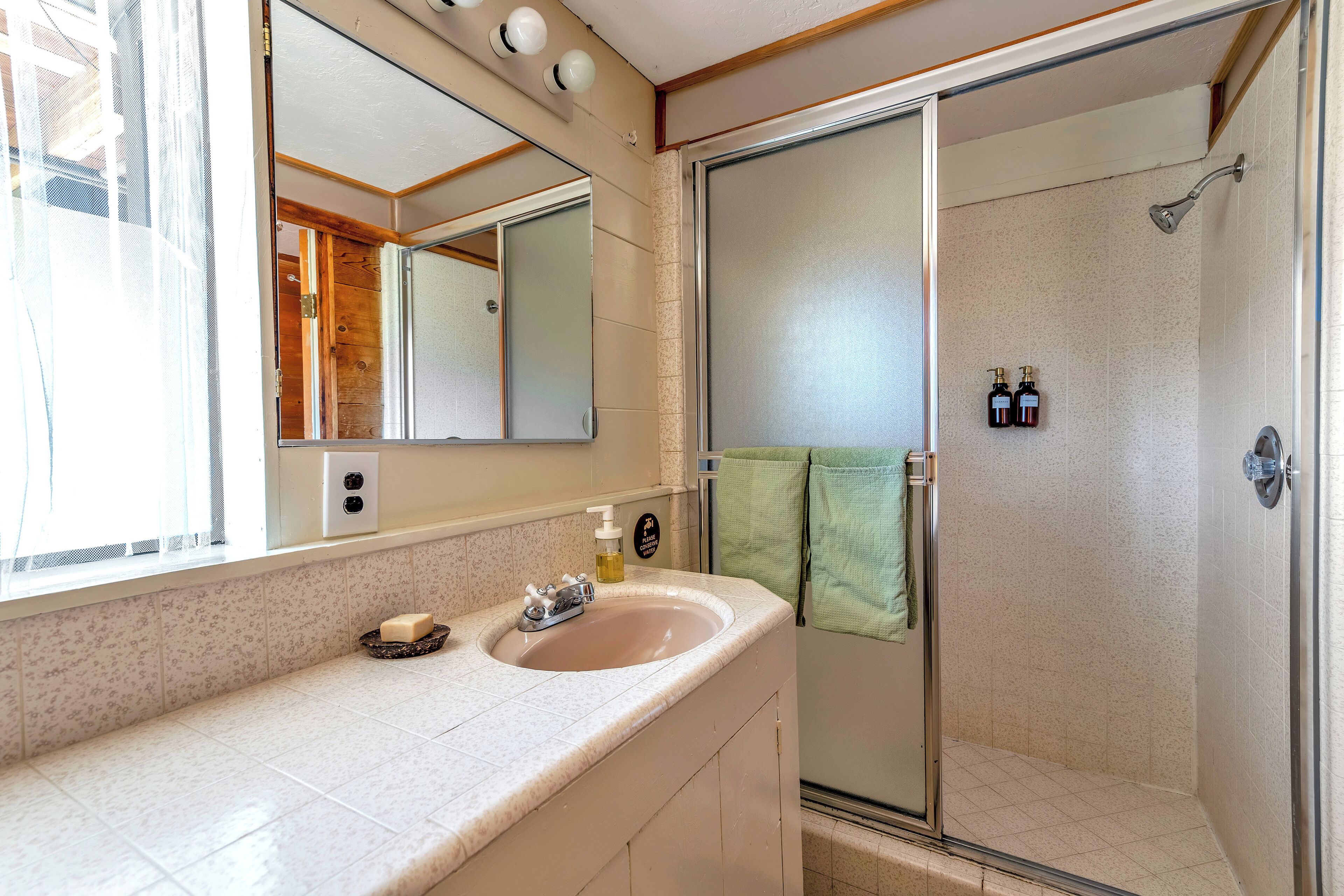 Een badkamer met een wastafel, spiegel en douche.