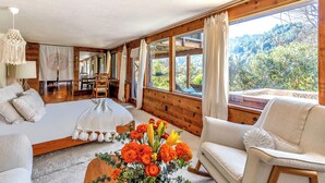 Une pièce confortable avec un grand lit, un fauteuil à bascule et une vue sur une montagne boisée.