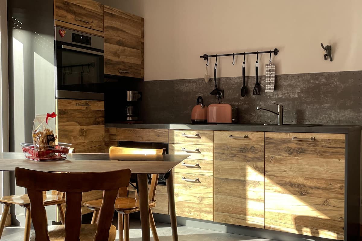 Una cocina moderna con armarios de madera, un refrigerador de acero inoxidable y una cafetera.