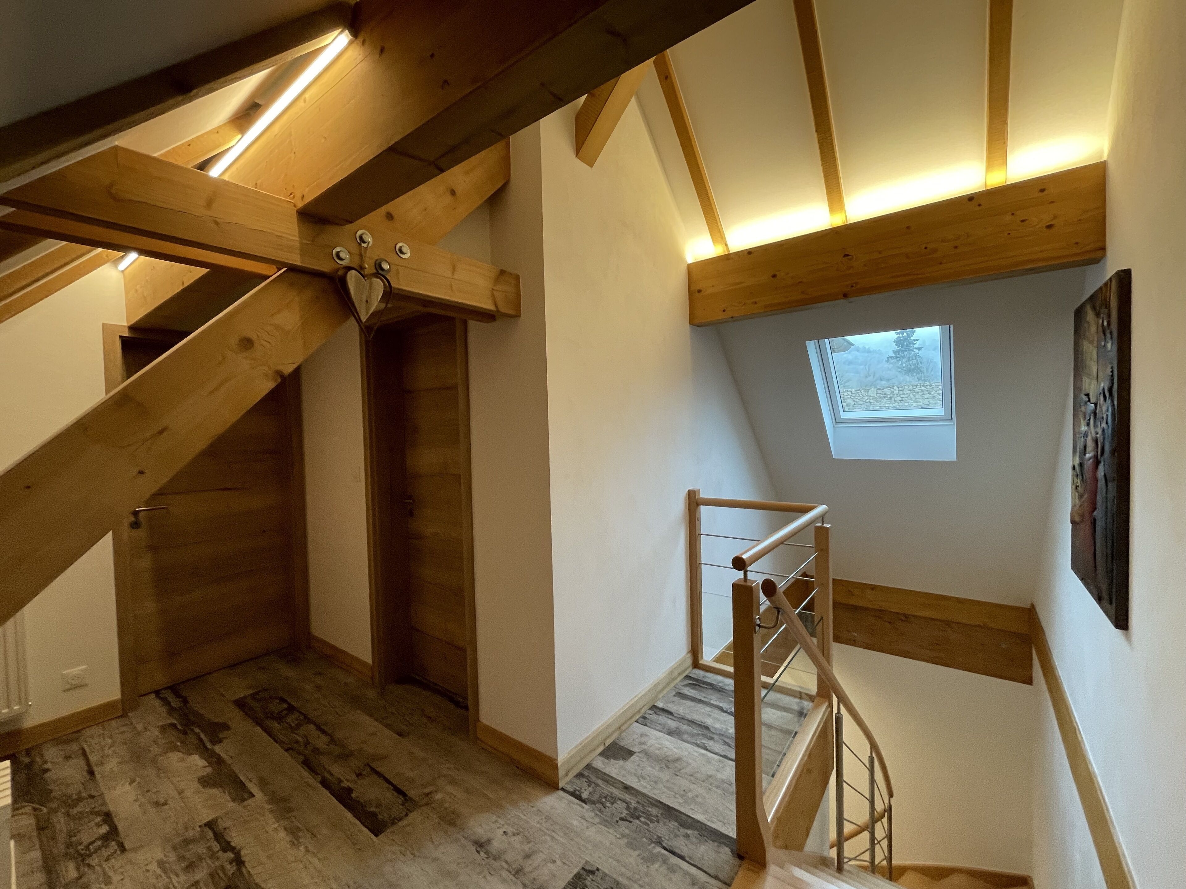 Eine Holztreppe mit Oberlicht, einer Holztür und einem Metallgeländer.
